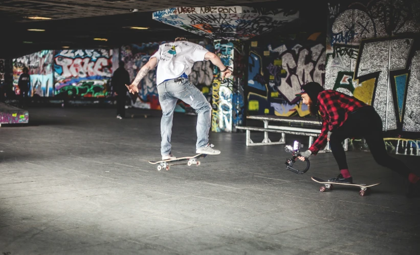 two men on skate boards in a graffiti covered area