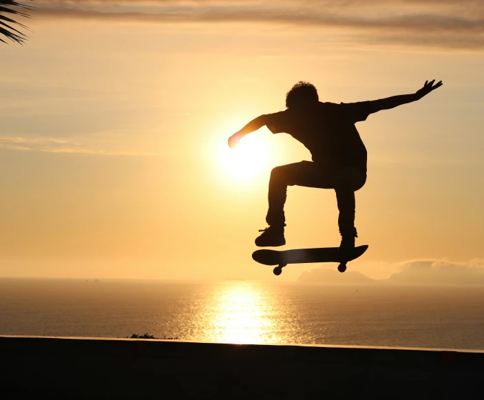 a man jumping on top of a skateboard on a hill