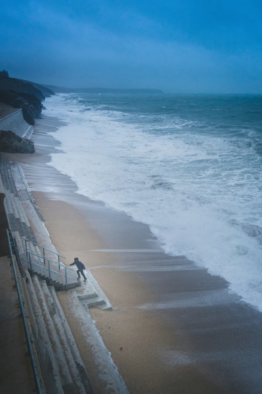 a man standing on the boardwalk looking out to sea