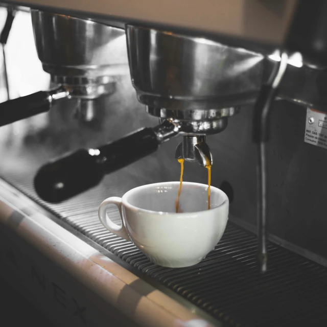 coffee being poured into a mug at the bottom of a machine