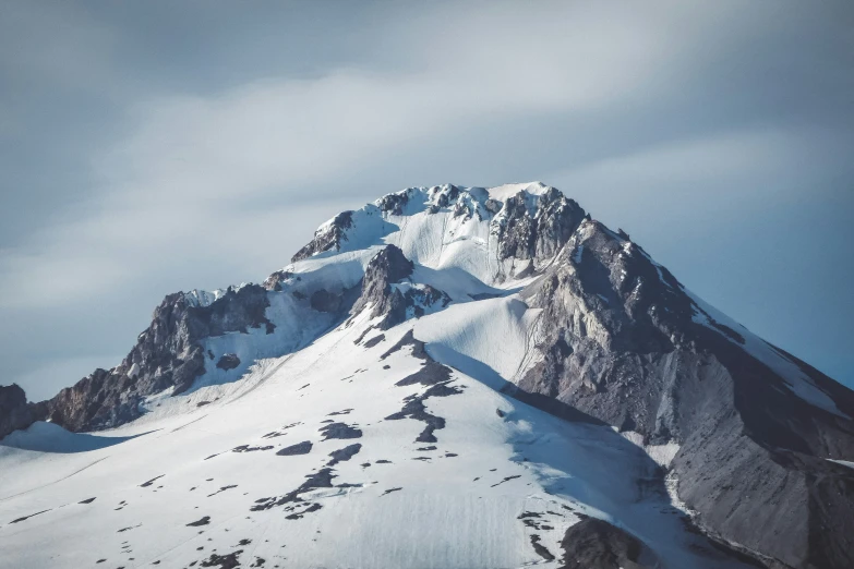 snow covered mountains under a cloudy sky with lots of trees