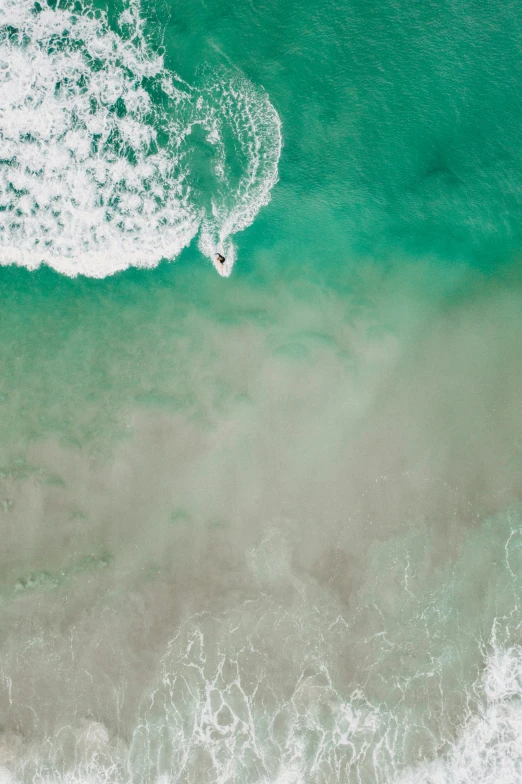 an aerial view of two surfers riding waves in the ocean