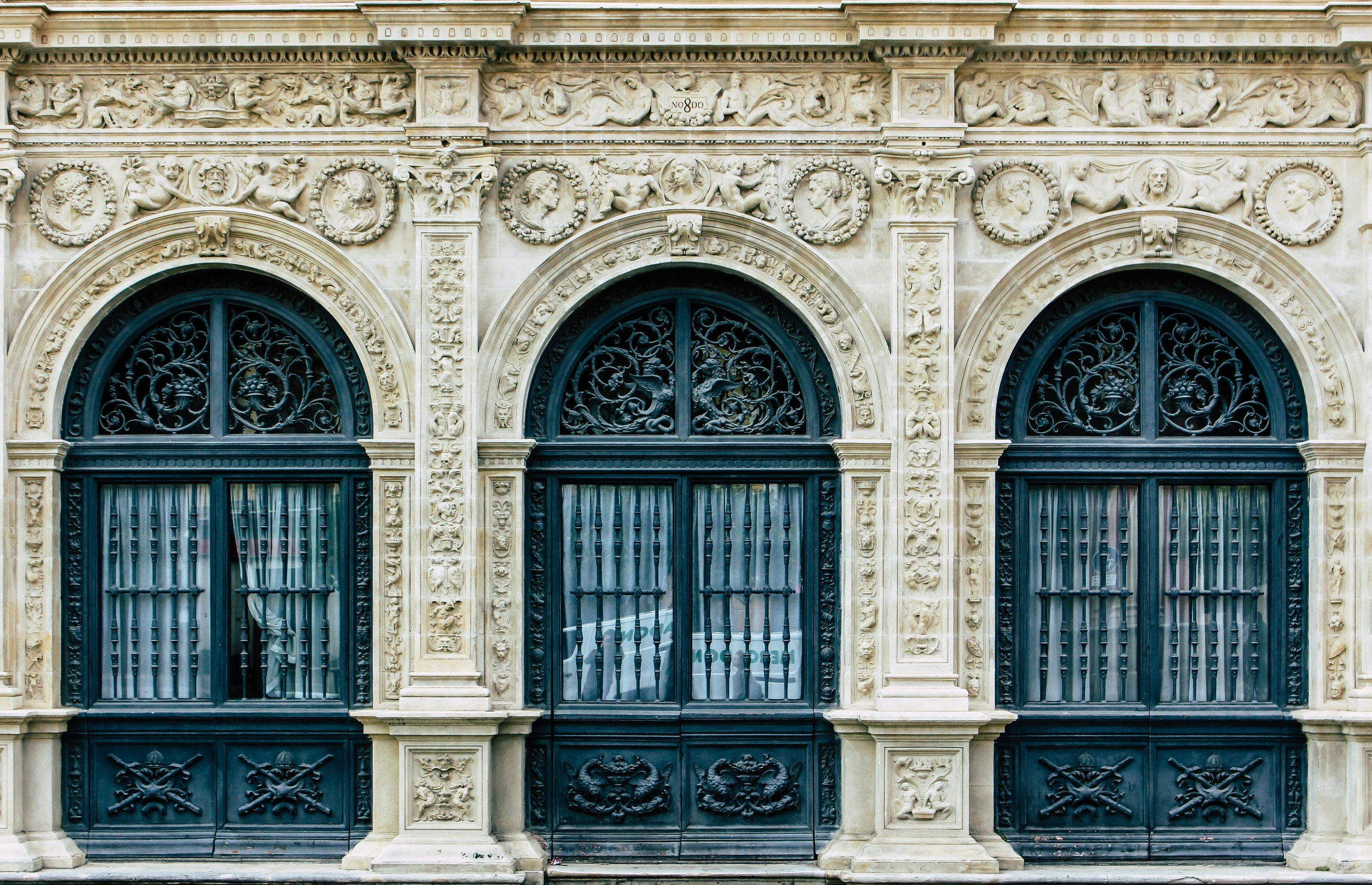 a woman sits outside a building with ornate iron windows