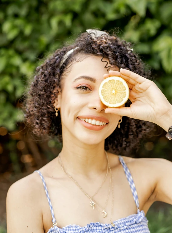 a woman holding up a slice of lemon to her face