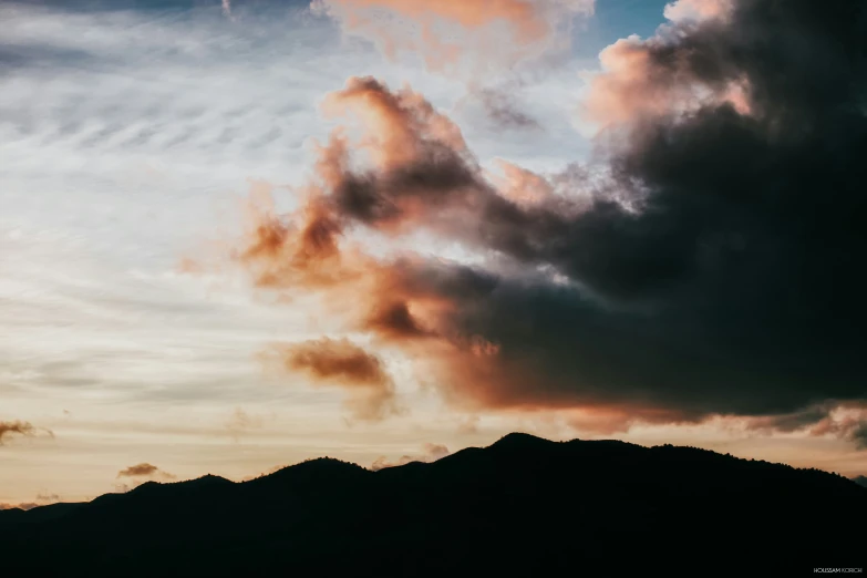 a plane flying over a mountain and some clouds