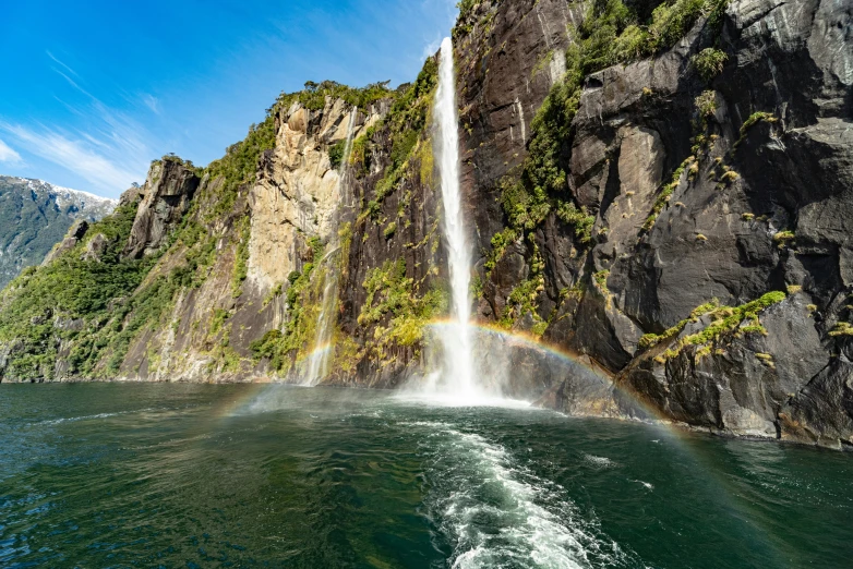 a waterfall with a rainbow above water