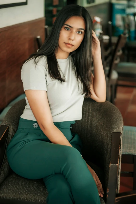 an asian woman in a white top, green pants and black heels