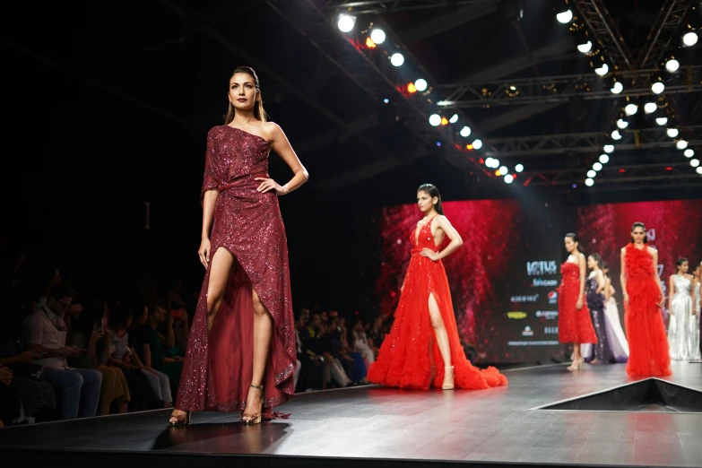 two models in one gown and one in red is walking down the runway