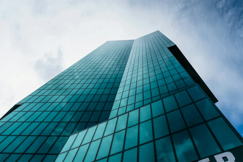 a very tall glass building on top of a cloudy day