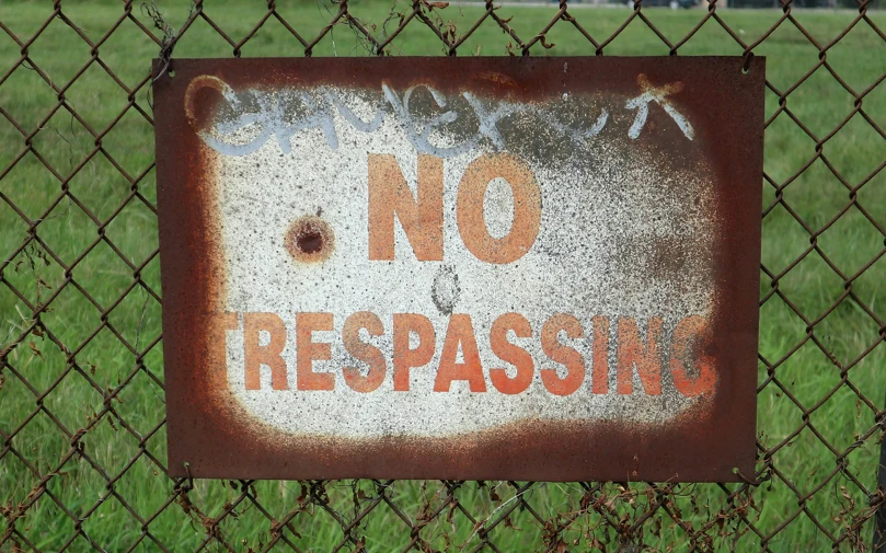 a no trespassing sign placed behind a fence