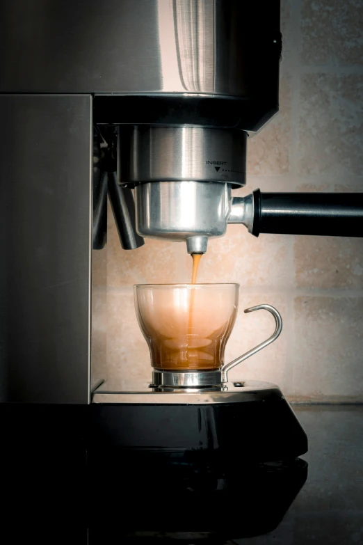 espresso coffee being poured into glass cup in kitchen setting