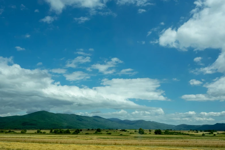 the view from a vehicle of a field with mountains in the distance