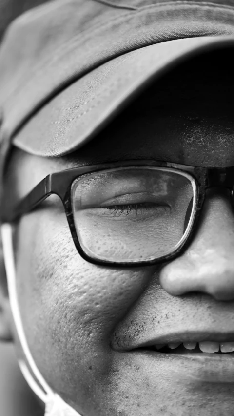 a man in glasses and a hat looks at the camera