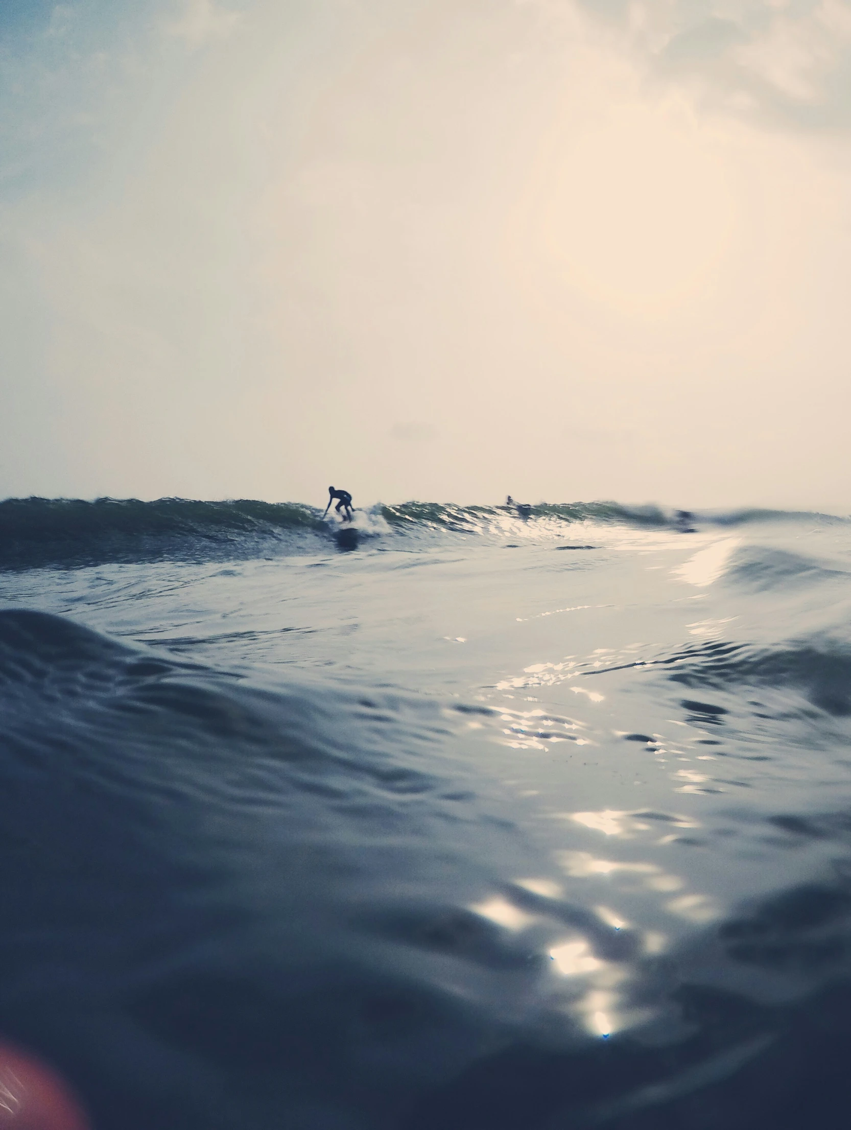 surfer in the ocean riding a wave under a cloudy sky