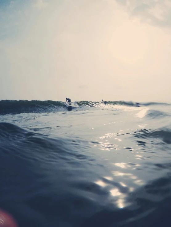 surfer in the ocean riding a wave under a cloudy sky