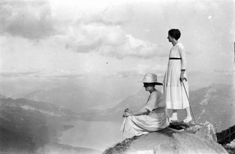 two women standing at the top of a cliff on the same side as one another