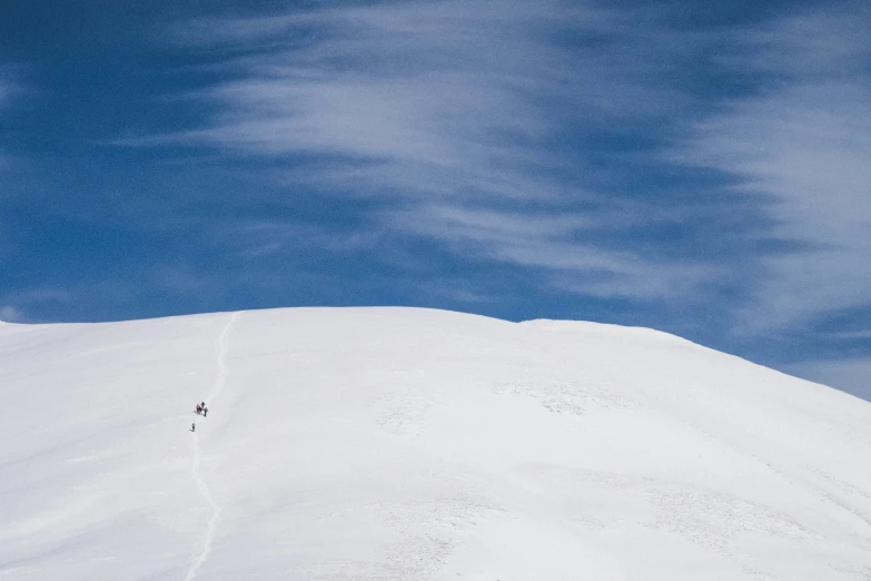 a person skiing down a snowy hill in a blue sky