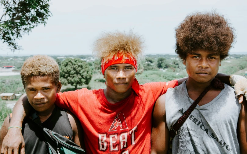 three men are posing for the camera with a bush behind them