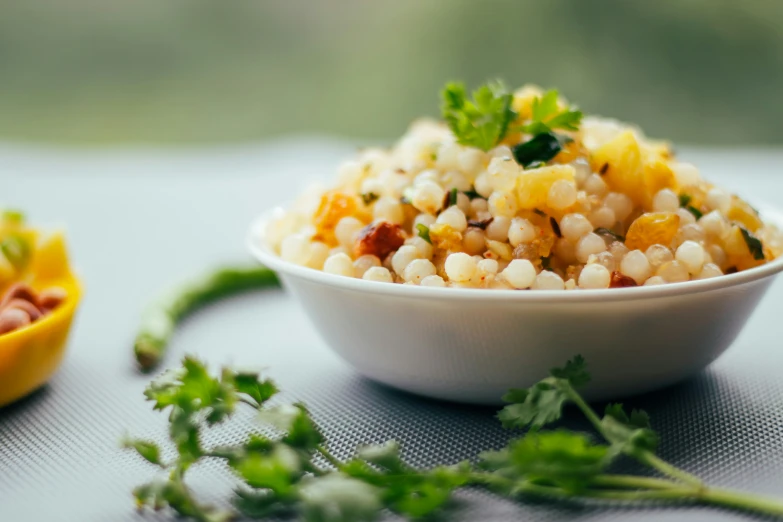 a corn salad sits in a white bowl next to a half eaten fruit