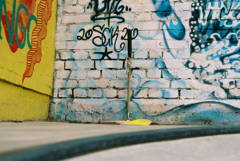 a skateboarder riding down the sidewalk next to graffiti on a wall