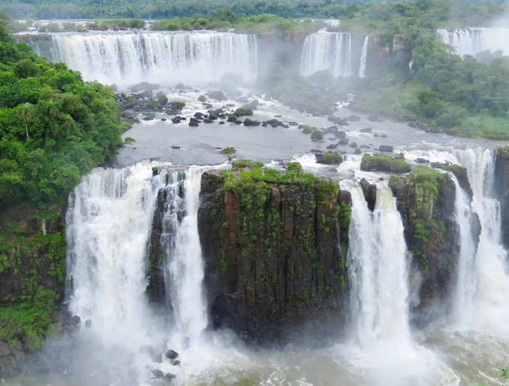 a group of people standing next to two huge waterfalls