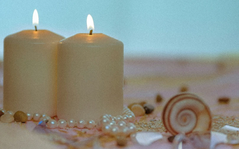 two lit candles next to shells and a sea shell