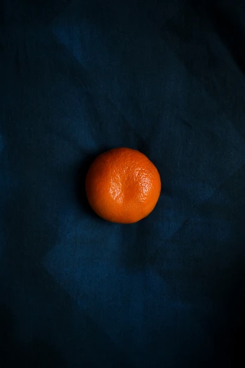 an orange sitting on a dark colored surface