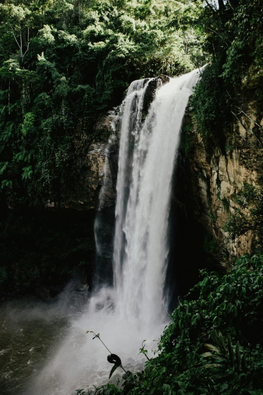 a person with a paraglider is sitting in front of a waterfall