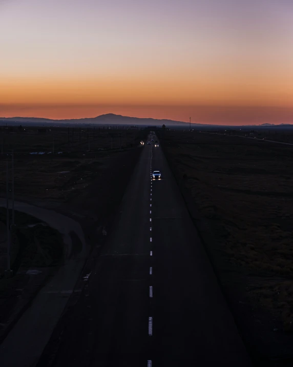 a lonely road sits next to the highway at dusk