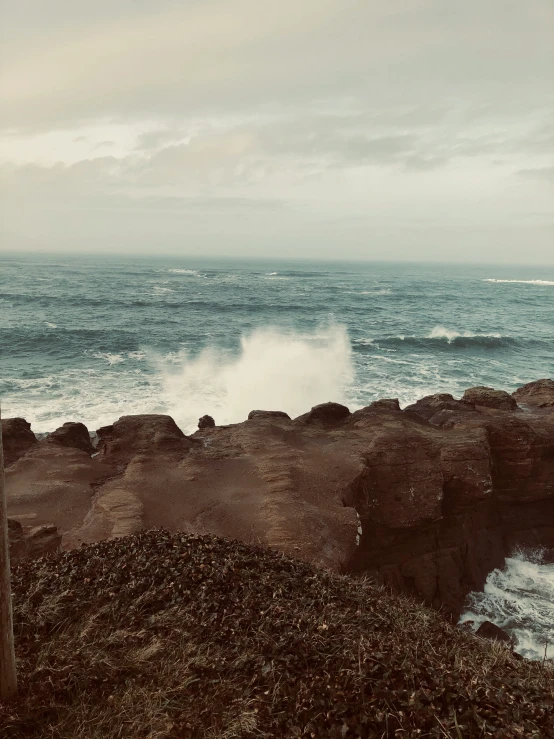 waves are crashing on the rocky shore next to the ocean