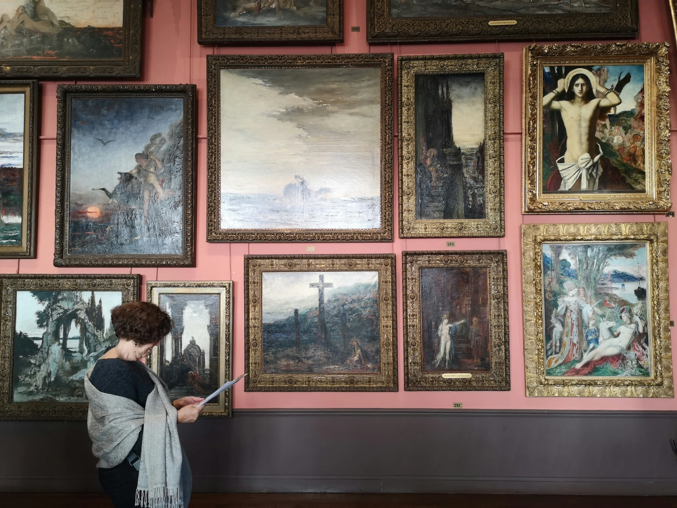 a woman looks at paintings on display in an museum