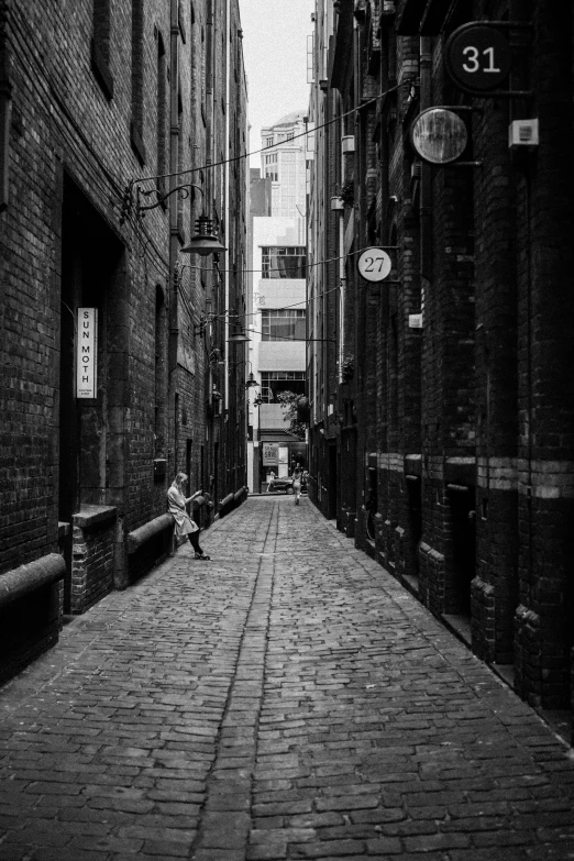 a person sitting on a wall in a dark alleyway