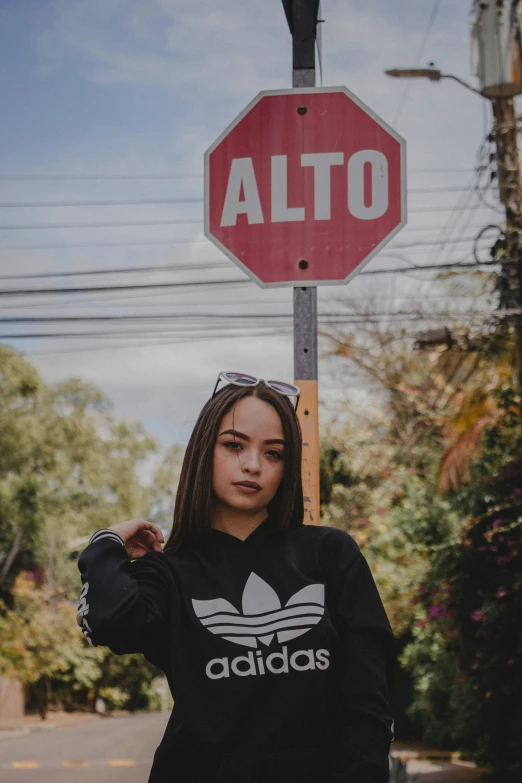 girl with black hoodie standing underneath a red sign