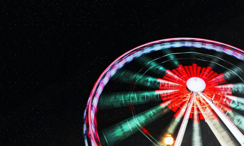 a brightly lit carnival wheel on a dark sky day