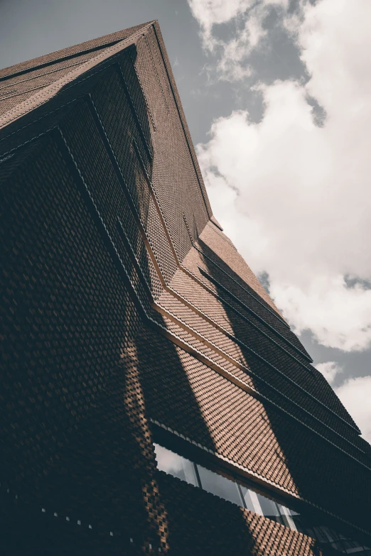 a very tall brick building under a blue cloudy sky