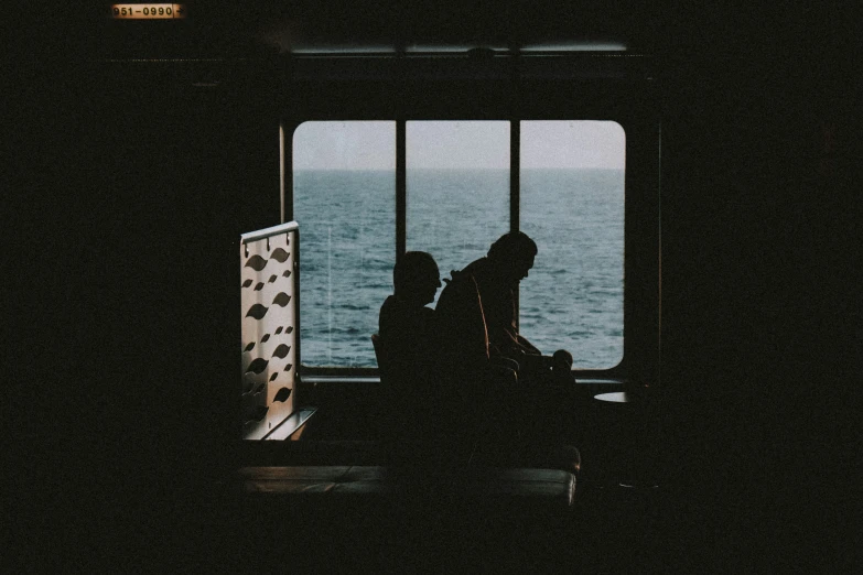 a silhouette of two people in a darkened room by the water