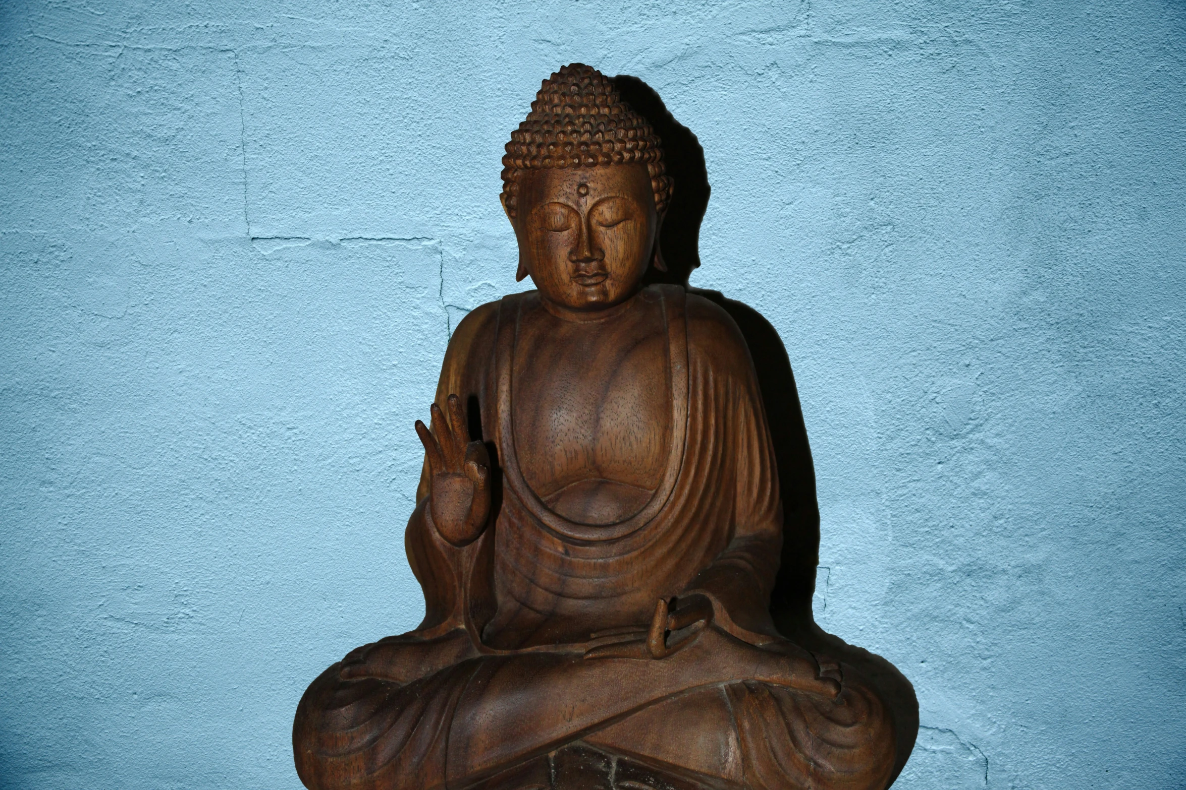 a buddha statue sitting in front of a wall