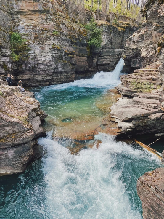 a waterfall flowing over the side of a canyon next to rocks