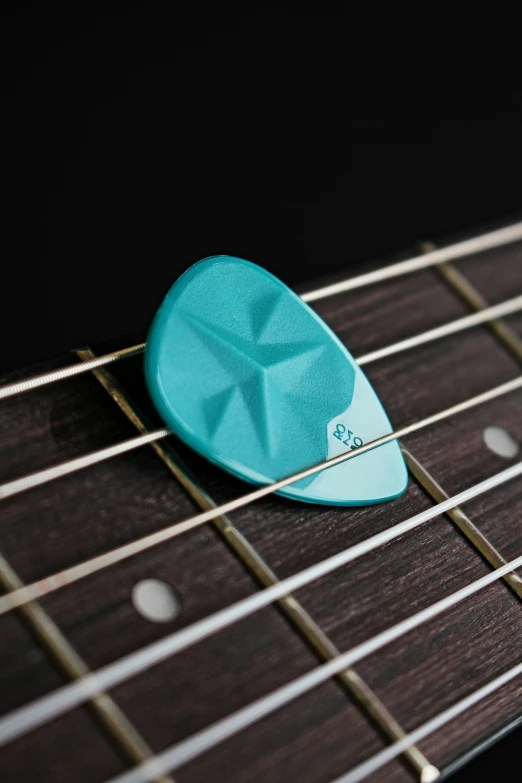 a blue guitar pick that has been left on an acoustic guitar