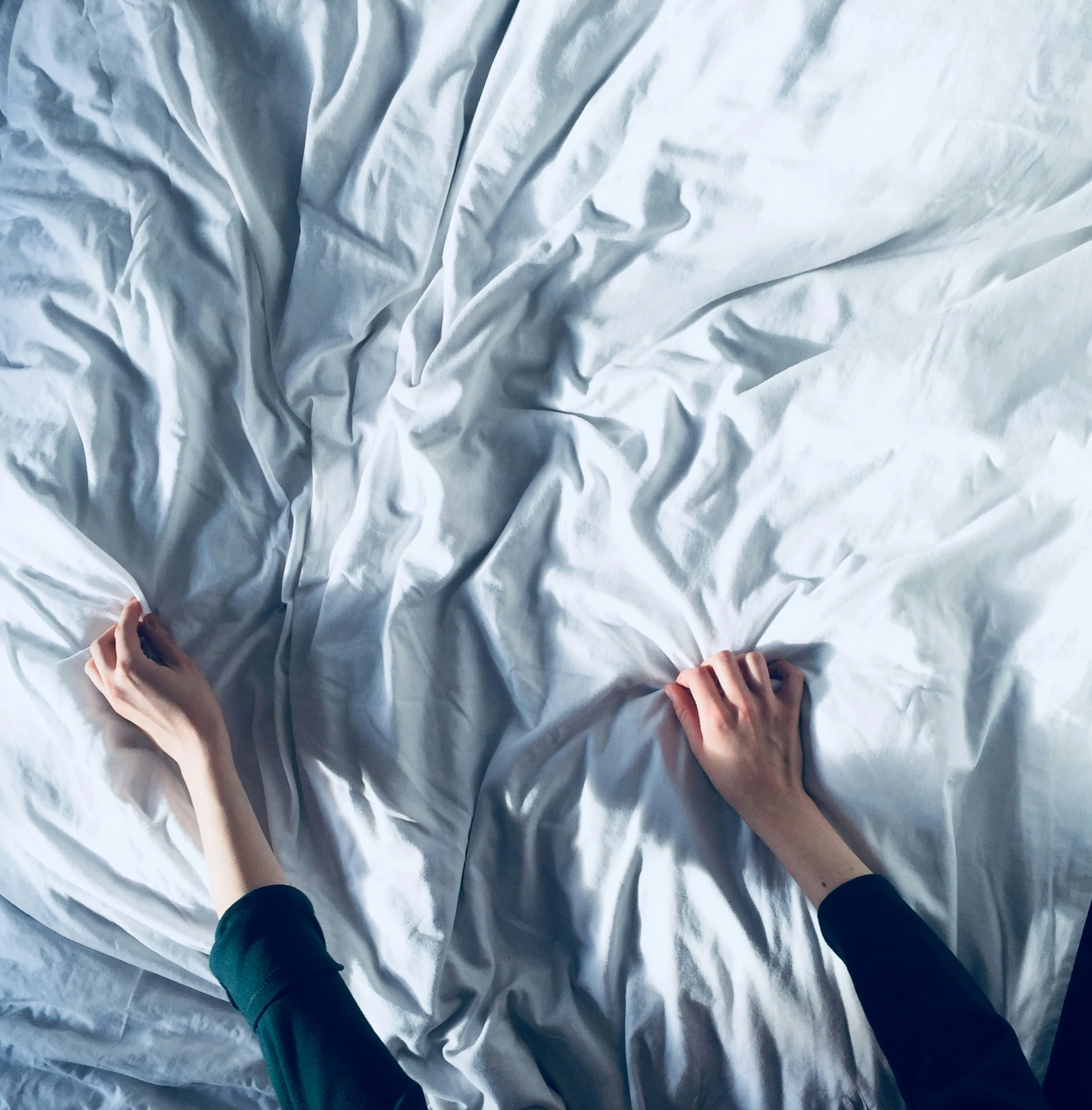 someone's legs laying in a white bed with sheets