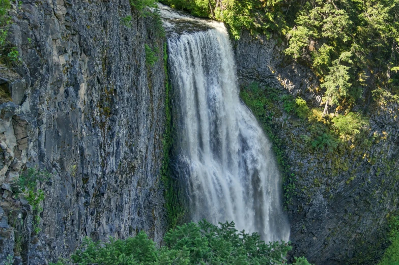 a waterfall that is over a cliff and above some trees