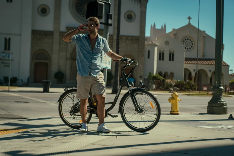 a young man poses with his bike in front of a church