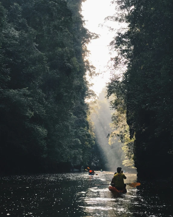 a canoe with two people in it traveling down a river