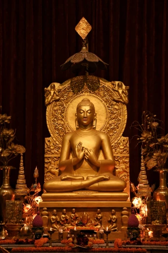 golden buddha statue with decorative lights next to red curtains