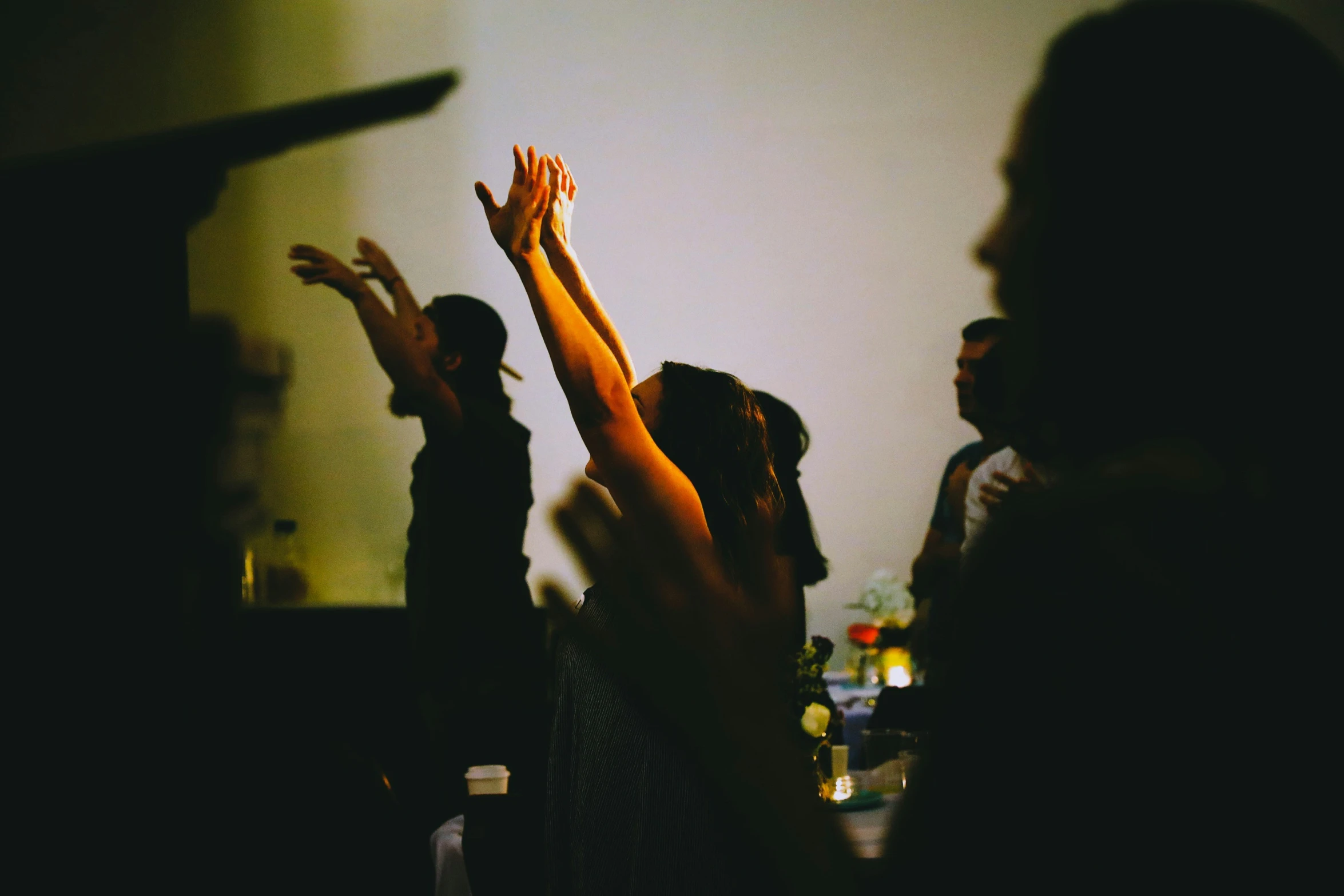 three young women raising their hands up in a group