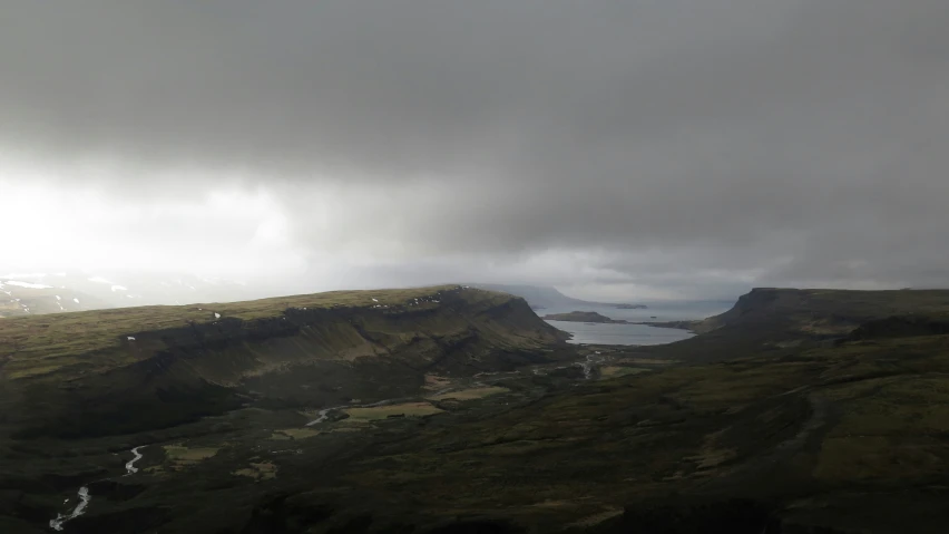 the clouds are over the mountains and river in the valley