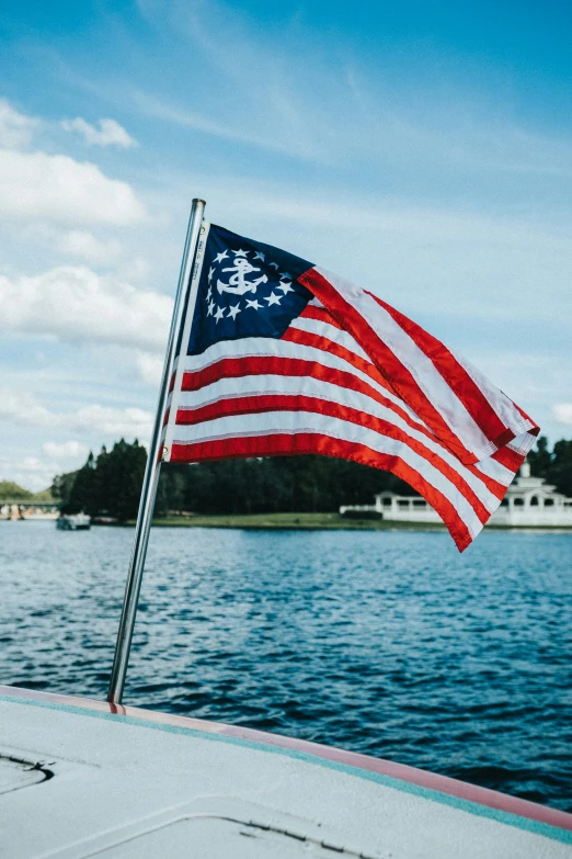 the american flag is waving near the water