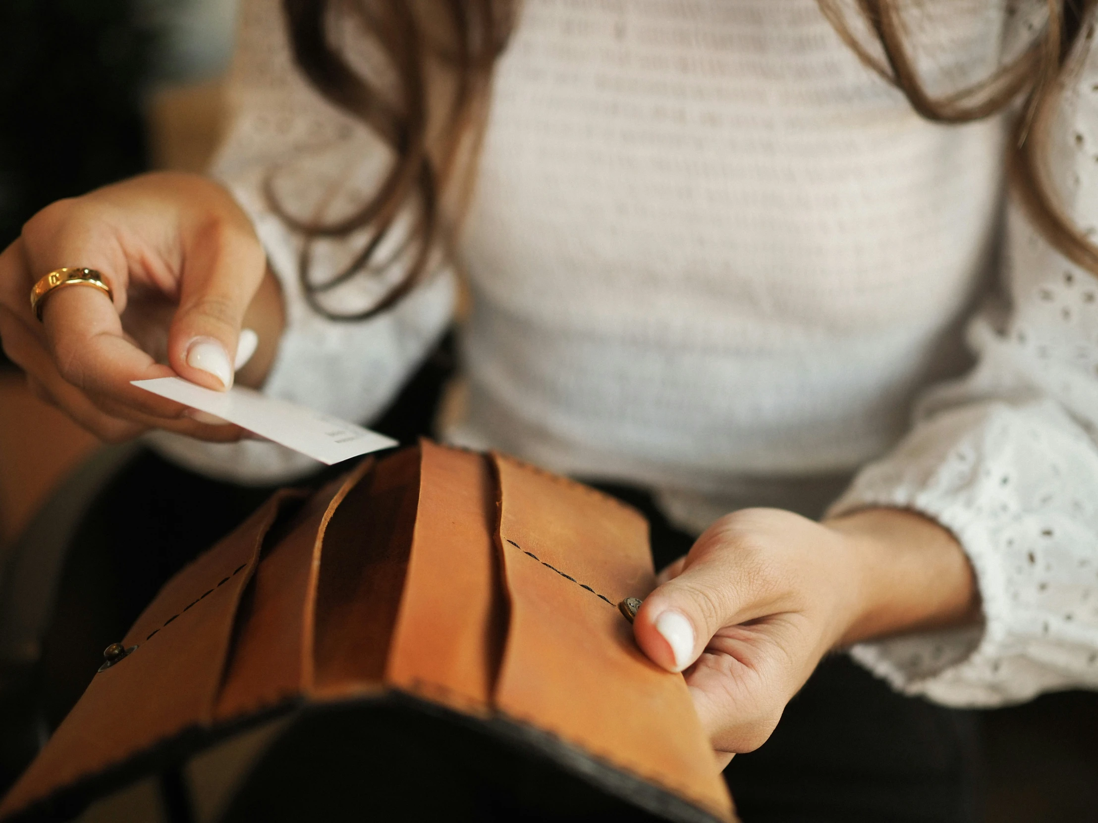 close up of person's hands holding out a folded wallet