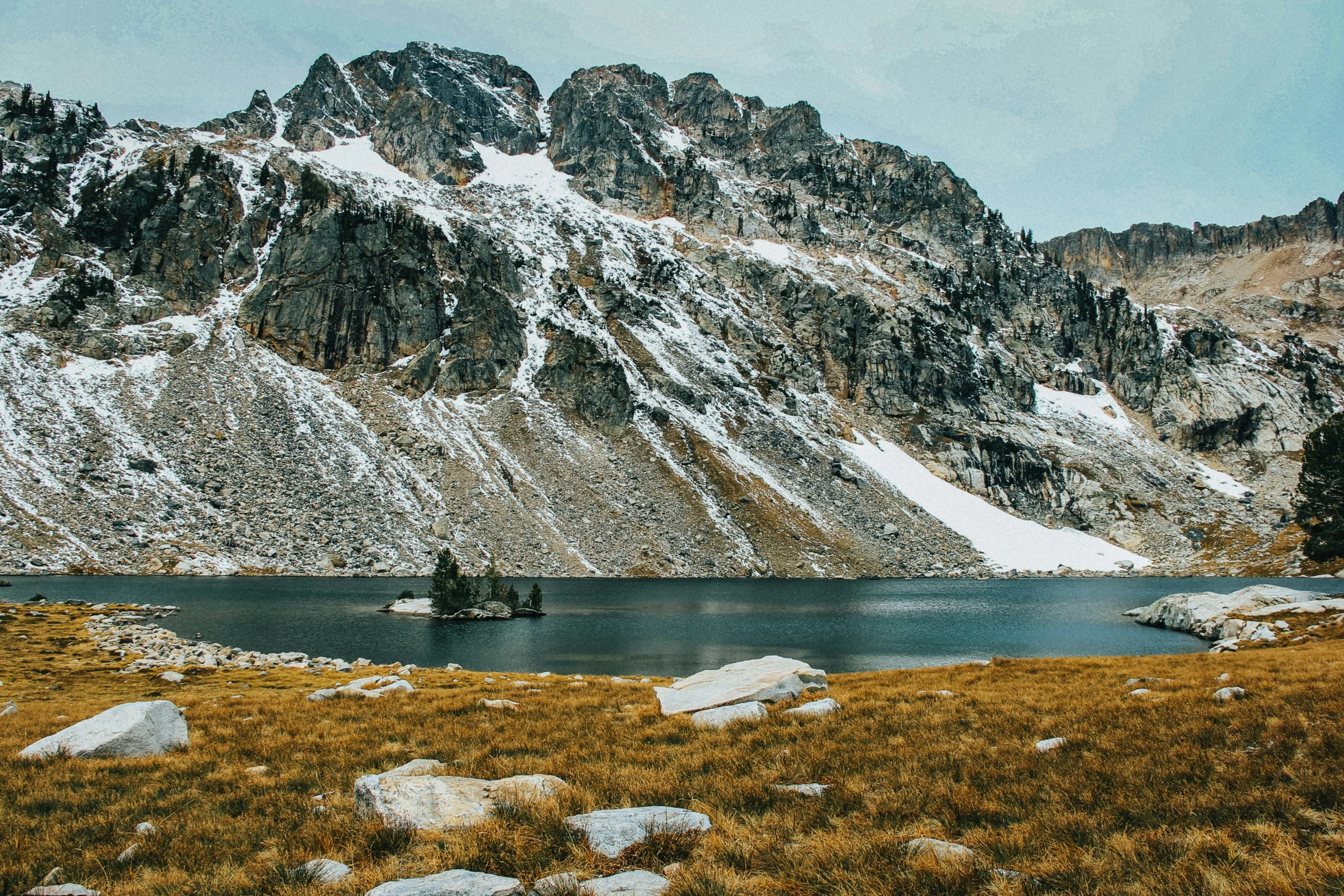 a small boat sits out in the water near a mountain range