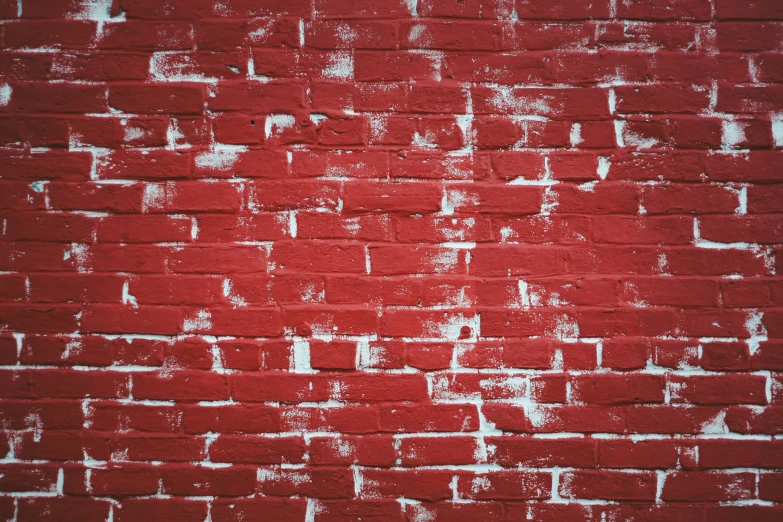 red brick wall with white paint peeling off the edges